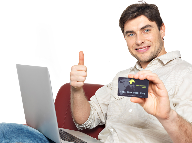 Portrait of smiling happy man with laptop gives the thumbs up and shows the credit card isolated on white.